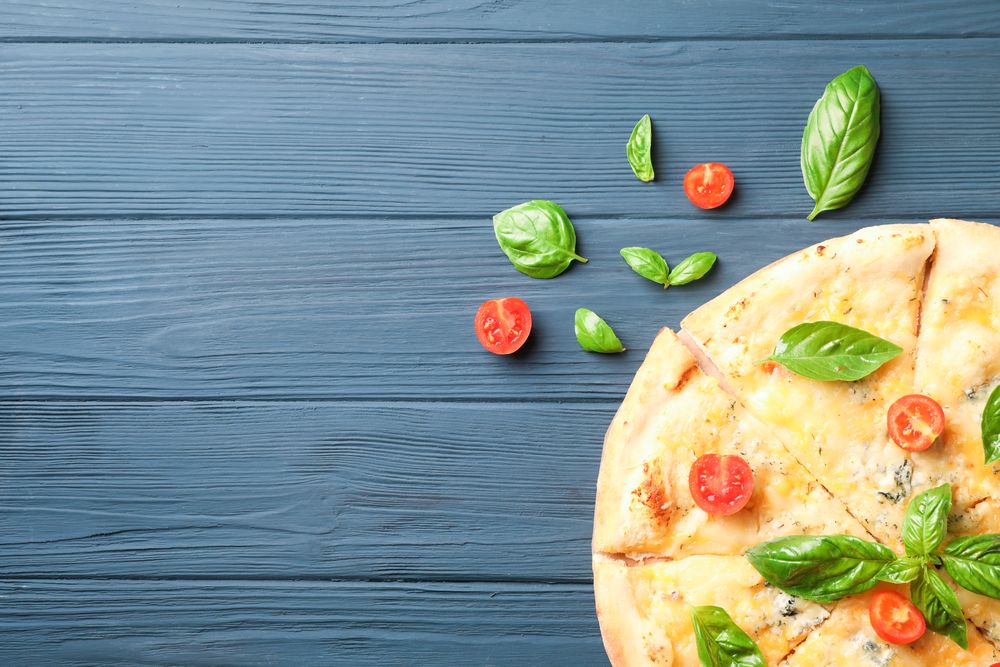 Cheese pizza with tomatoes and basil on wooden background, copy space