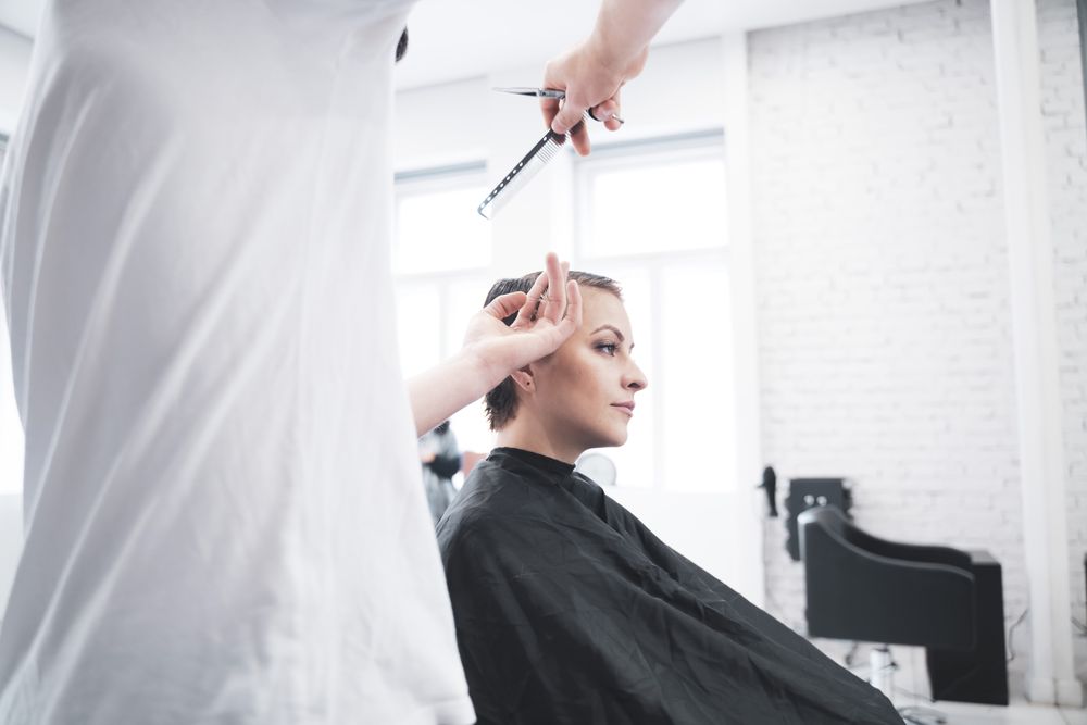 Hairdresser cuts woman's hair with scissors