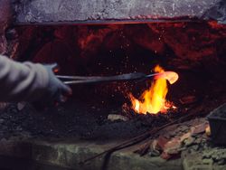 Crop blacksmith heating metal in furnace