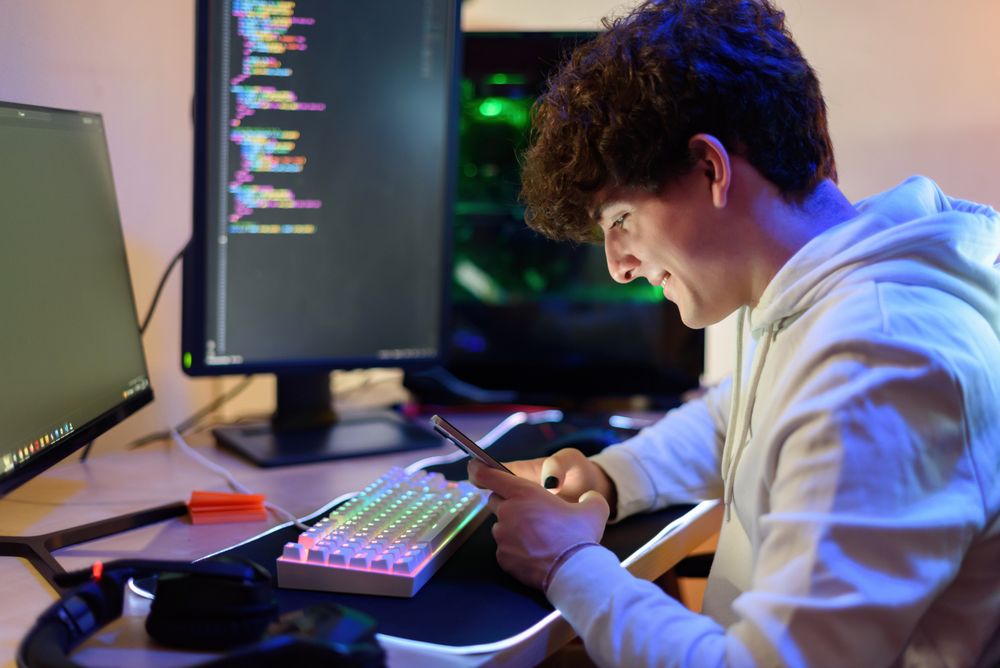 Focused happy young man sitting in chair and checking messages on smartphone