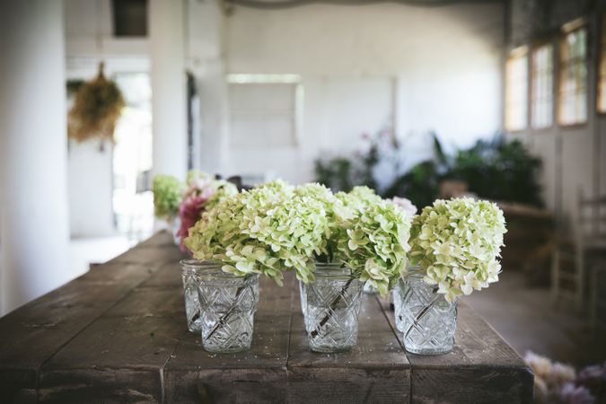 Table with set of flowers in glasses in room
