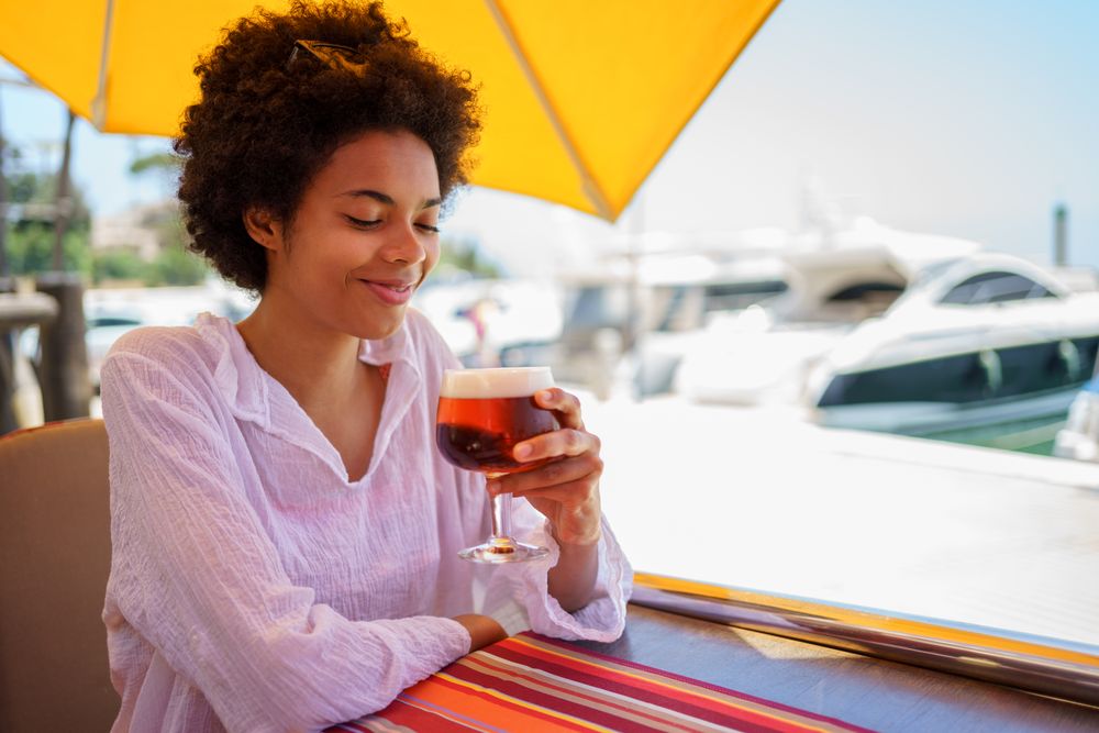 Woman with glass of beer at cafe on the harbor