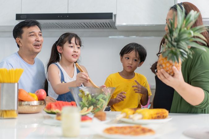 Happy Asian family cutting fruit in the kitchen together