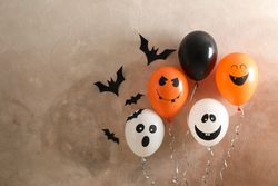 Different balloons on brown background. Halloween concept, space for text