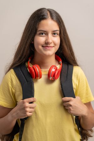 Portrait of a smiling young student holding her backpack, ready for back to school.