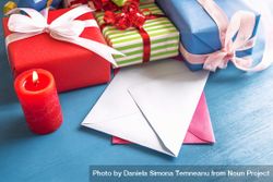 Colorful gifts and blank envelops on blue table 5on8Q0