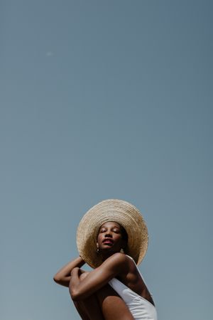 Woman in a light swimsuit wearing a large sun hat
