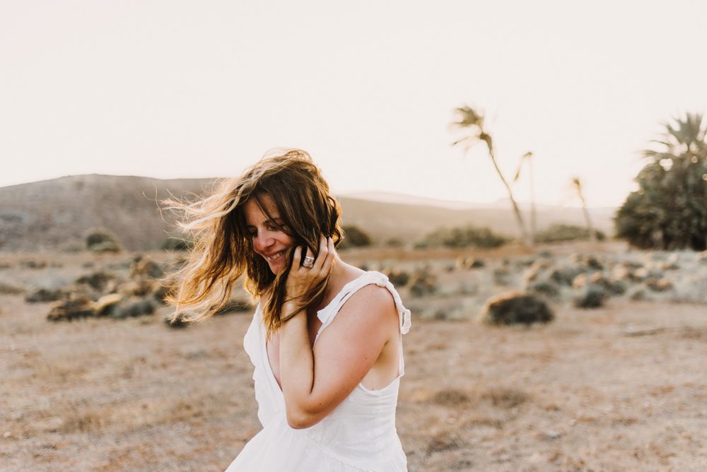 Woman in white dress in dry field in sunlight