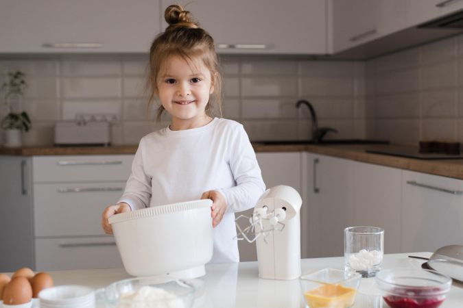 Young girl holding light bowl in the kitchen