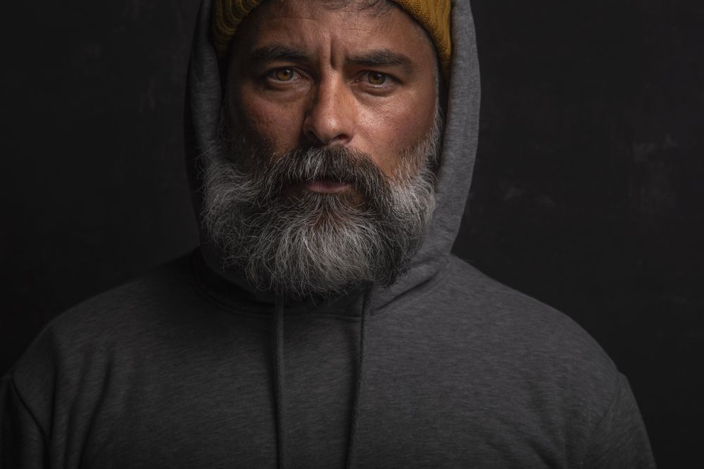 Portrait of middle aged man with gray hoodie with gloomy expression against