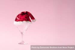 Martini glass with sequin Santa hat on pink background 56DKLb