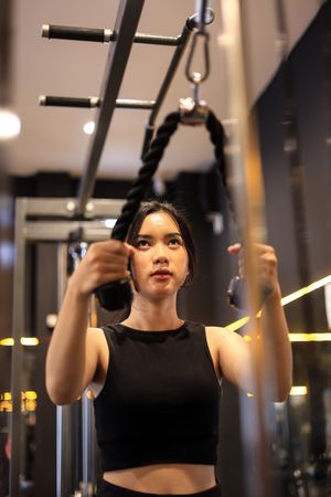 Woman doing Cable Arm Exercises at the Gym, using the Rope Attachment for Triceps Push Down.