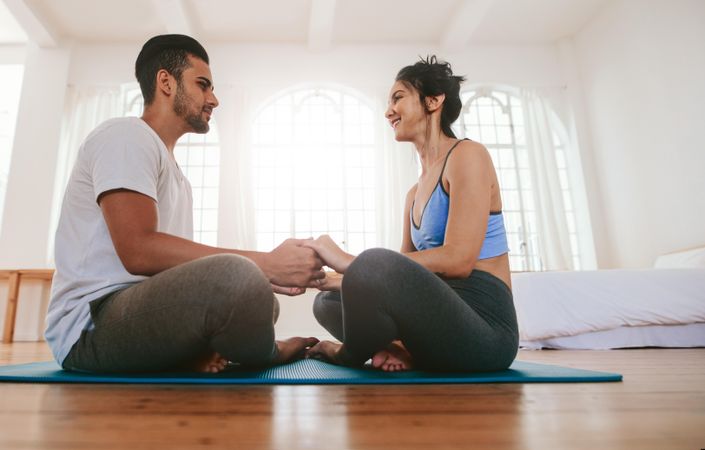 Low angle of smiling woman looking at boyfriend while meditating