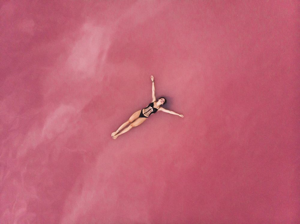 Carefree woman on vacation delighting in pink water of lake