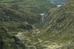 Empty green valley at foot of mountain hills