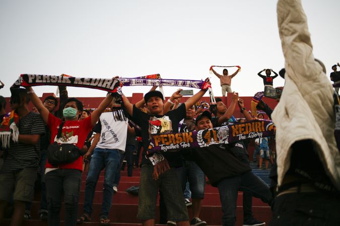 Kedira, East Java Indonesia - October 4, 2019: Soccer fans holding scarfs up of their favorite team