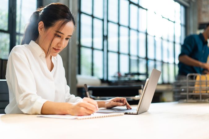 Female taking notes from laptop in office