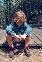 Sad preteen boy sitting on wooden boardwalk
