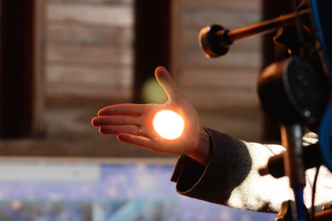 Man holds his hand up, capturing focused telescope light.