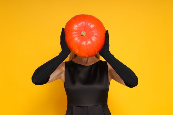 A woman in a Halloween outfit, with a pumpkin instead of a head