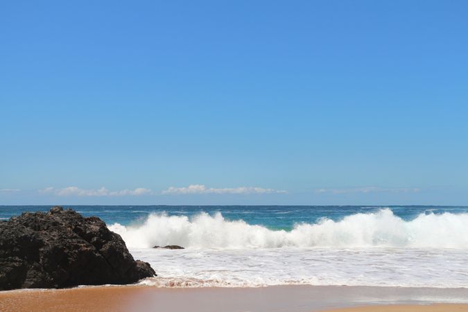 Serene beach with crashing waves and clear blue skies during a sunny day in a coastal region