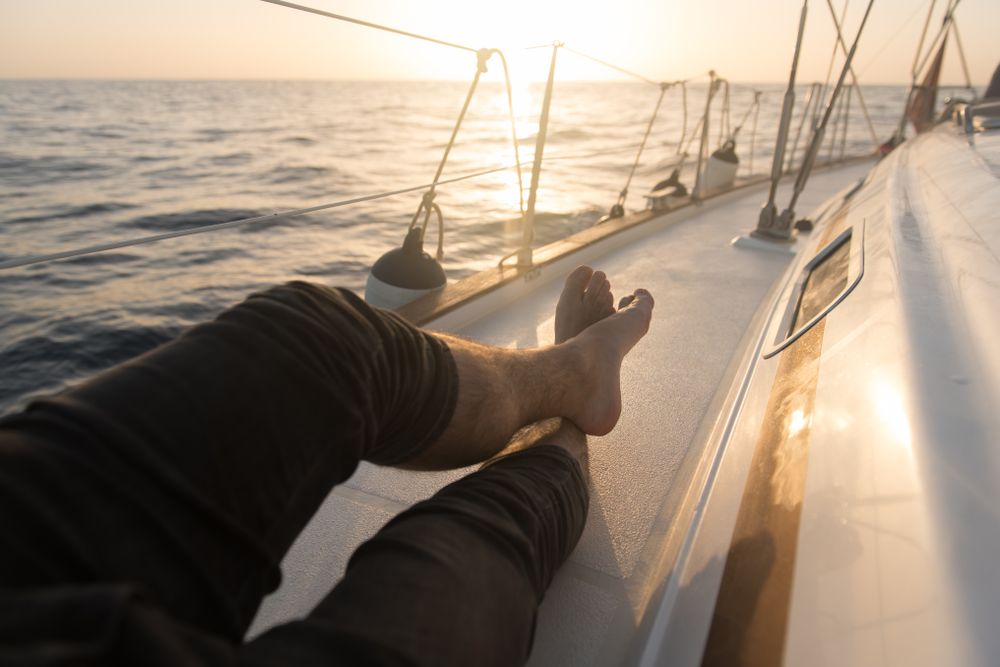 Man lying on edge of yacht on water