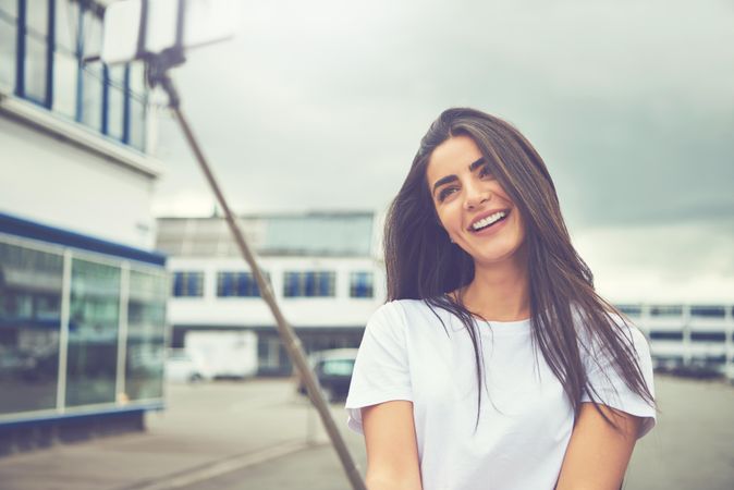 Happy woman smiling into selfie stick as she takes a photo of herself
