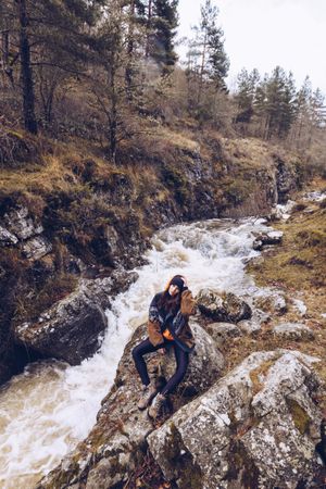 Woman gazing at fast mountain river in forest