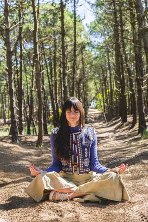 Portrait of an adult woman with her eyes closed while meditating on the woods. Vertical shot