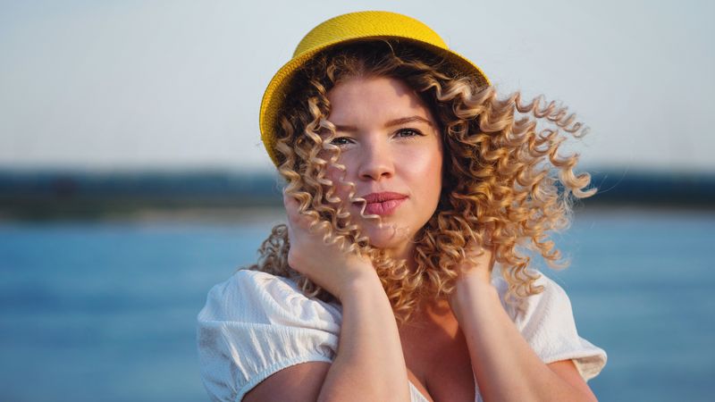 Portrait thoughtful woman in yellow hat outdoors