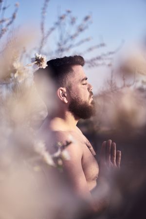 Shirtless man meditating in spring garden