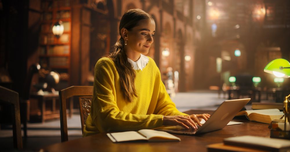 Focused Young Woman Studying in a Classic Library, Using Laptop for Online Education
