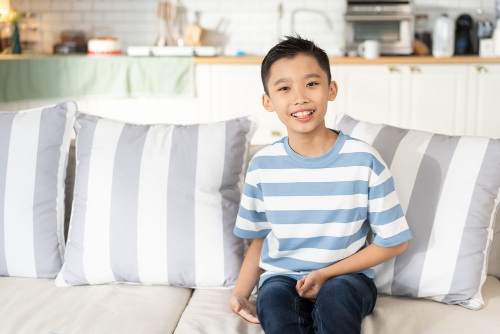 Portrait of Asian boy sitting on couch in the living room looking at camera