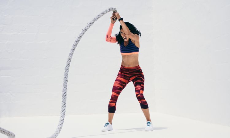 Tough woman working out using battle rope
