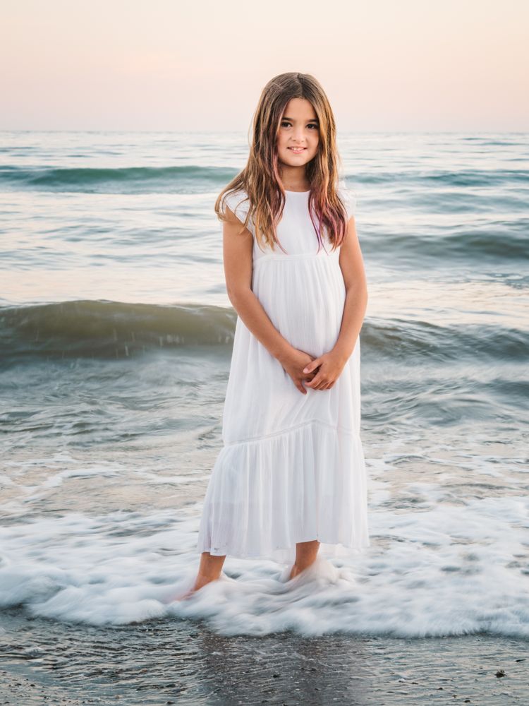 Smiling girl standing on seaside among waves