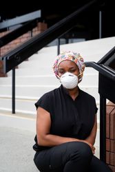 Portrait of confident woman nurse in scrubs, scrub hat and N95 mask smiling and looking at camera