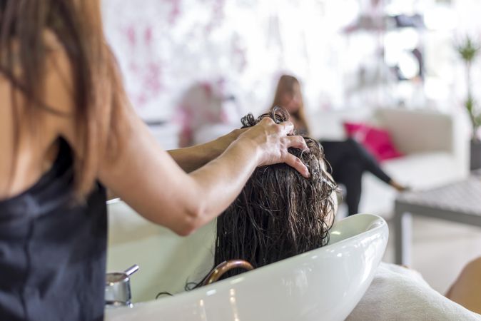 Woman having her hair rinsed in sink at salon