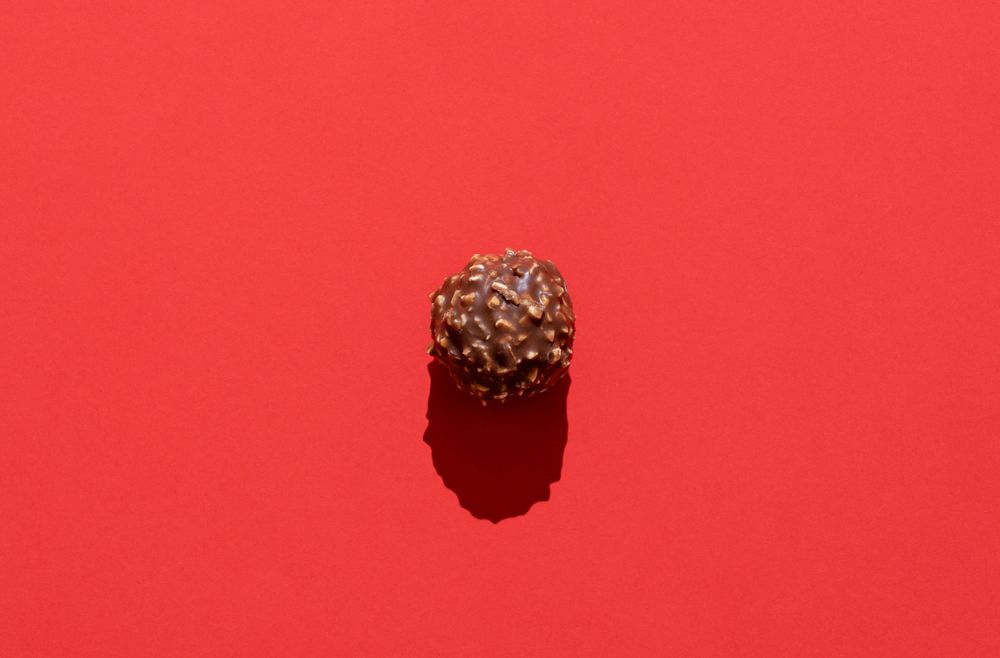 Chocolate truffle minimalist on a red background in bright light