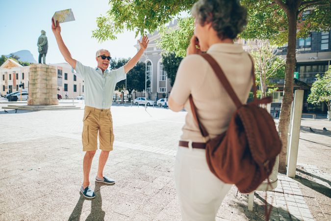 Woman taking photos of her excited husband in the city