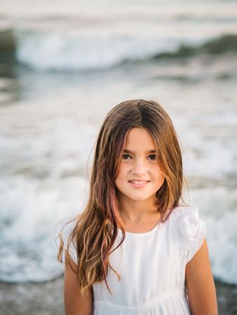 Smiling girl standing on seaside among waves