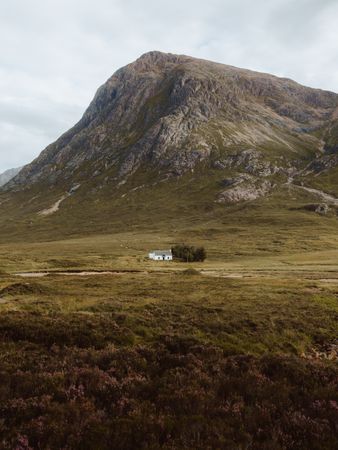 Lonely house in field by mountain
