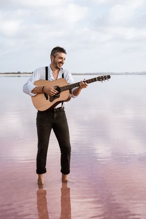 Inspired musician playing guitar at seaside