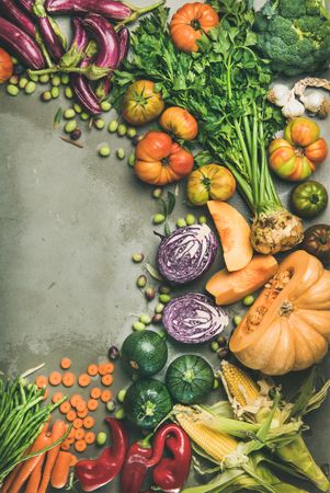 Fresh produce on concrete background, with halved squash, corn, cabbage, vertical composition