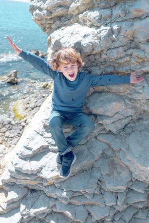 Delighted boy on cliff near sea