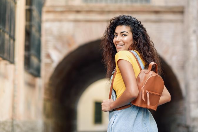 Happy Arab woman walking outside towards arch, copy space