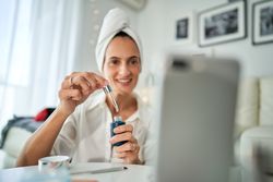 Cheerful woman with essence recording beauty blog