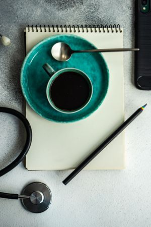 Top view of coffee cup with stethoscope, phone and notepad