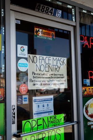 “No mask no entry” sign on restaurant door window