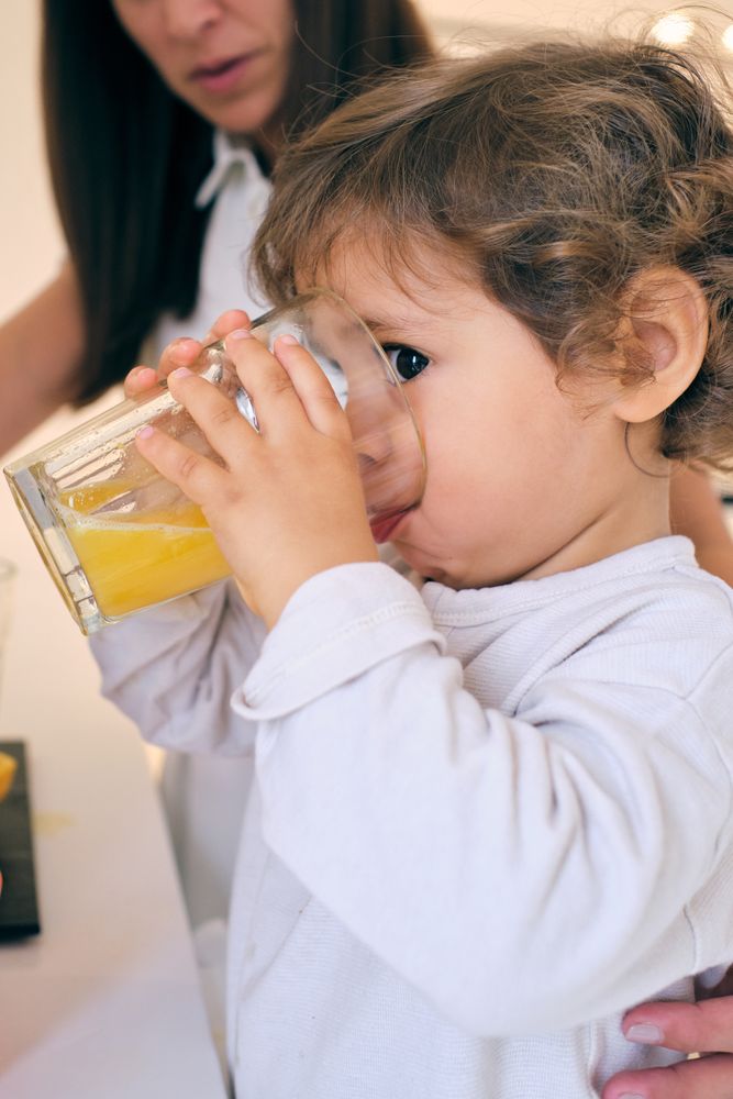 Cute kid drinking orange juice from glass