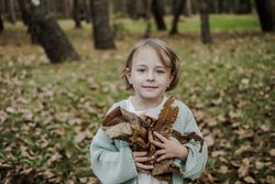 Girl with dry leaves between meadow in forest